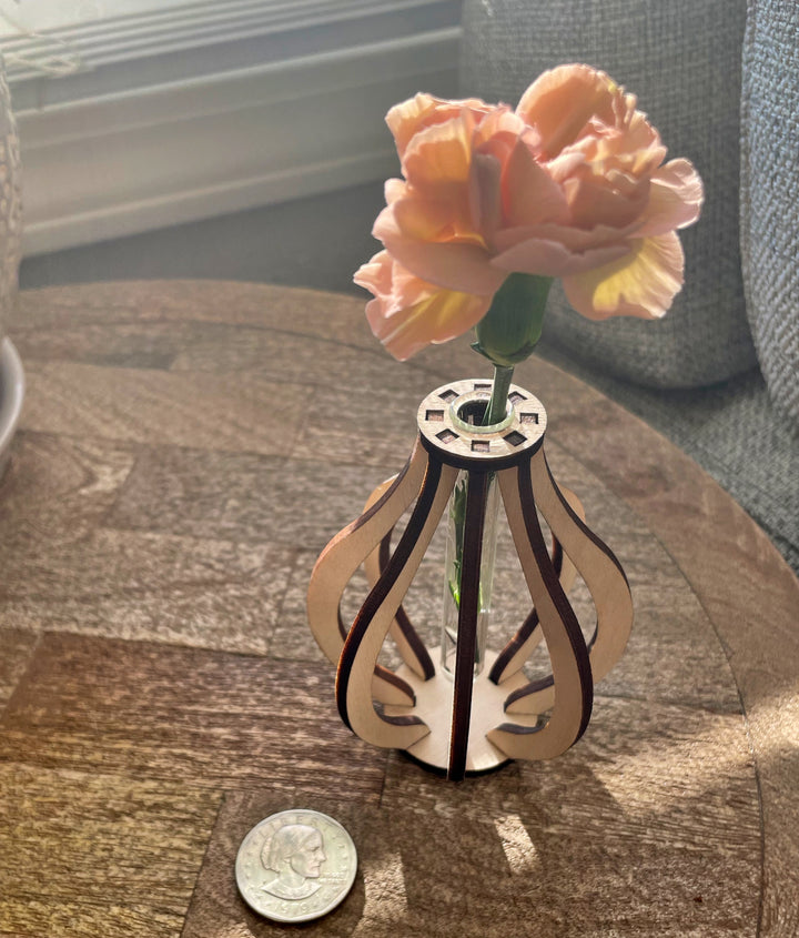 This small wooden bud vase is made from ten pieces of precision cut Baltic birch. At its center is a glass test tube to hold a fresh flower stem, cutting for propagation, or a dried floral bud.  SIZE: 3.5" tall 2.75" wide Mini test tube: 0.4" diameter   *DOES NOT INCLUDE PLANT Explore the best and coolest gift ideas for plant enthusiasts! Terra Cotta Plant Boutique serves the Toledo, Ohio area. Our online retail store ships nationally!