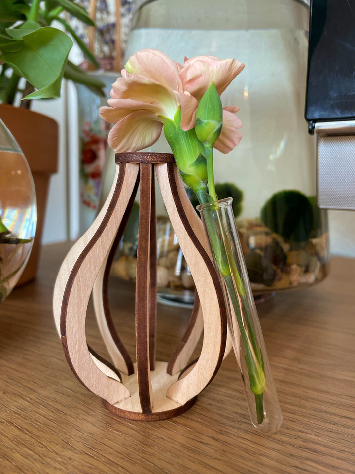 This small wooden bud vase is made from ten pieces of precision cut Baltic birch. At its center is a glass test tube to hold a fresh flower stem, cutting for propagation, or a dried floral bud.  SIZE: 3.5" tall 2.75" wide Mini test tube: 0.4" diameter   *DOES NOT INCLUDE PLANT Explore the best and coolest gift ideas for plant enthusiasts! Terra Cotta Plant Boutique serves the Toledo, Ohio area. Our online retail store ships nationally!