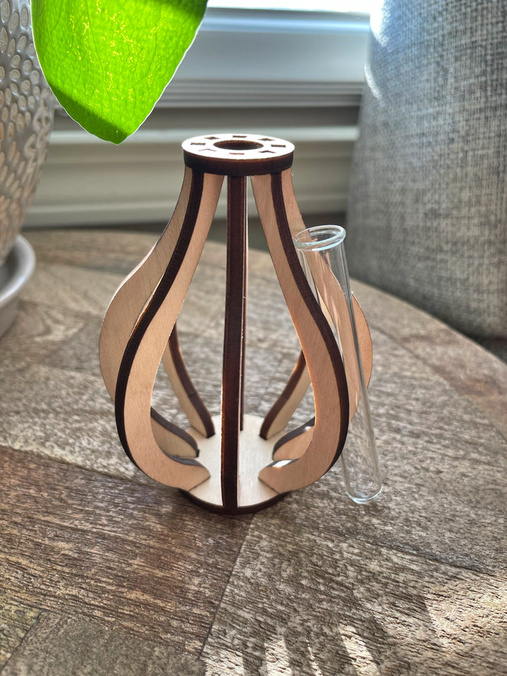 This small wooden bud vase is made from ten pieces of precision cut Baltic birch. At its center is a glass test tube to hold a fresh flower stem, cutting for propagation, or a dried floral bud.  SIZE: 3.5" tall 2.75" wide Mini test tube: 0.4" diameter   *DOES NOT INCLUDE PLANT Explore the best and coolest gift ideas for plant enthusiasts! Terra Cotta Plant Boutique serves the Toledo, Ohio area. Our online retail store ships nationally!