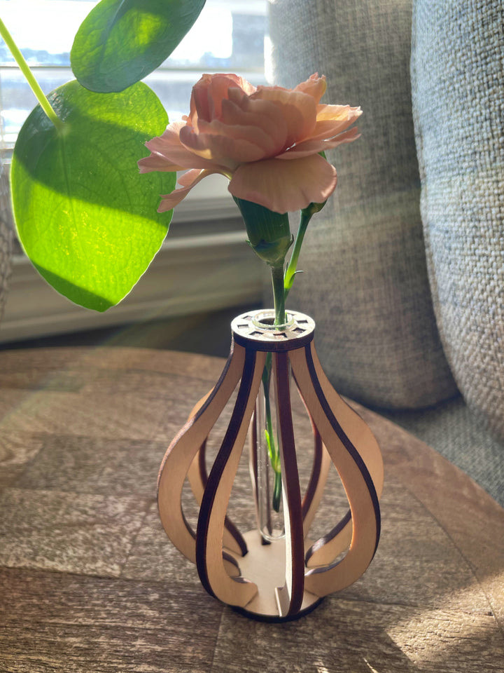 This small wooden bud vase is made from ten pieces of precision cut Baltic birch. At its center is a glass test tube to hold a fresh flower stem, cutting for propagation, or a dried floral bud.  SIZE: 3.5" tall 2.75" wide Mini test tube: 0.4" diameter   *DOES NOT INCLUDE PLANT Explore the best and coolest gift ideas for plant enthusiasts! Terra Cotta Plant Boutique serves the Toledo, Ohio area. Our online retail store ships nationally!