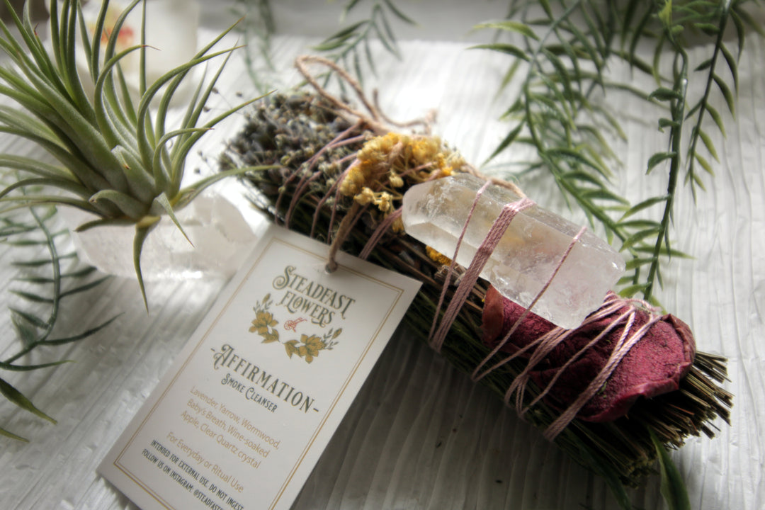 The affirmation smudge stick by Steadfast Flowers features lavender, yarrow, wormwood, baby's breath, wine-soacked apple, and clear quartz crystal. White-sage free! Explore the best and coolest gift ideas for plant enthusiasts! Terra Cotta Plant Boutique serves the Toledo, Ohio area. Our online retail store ships nationally!